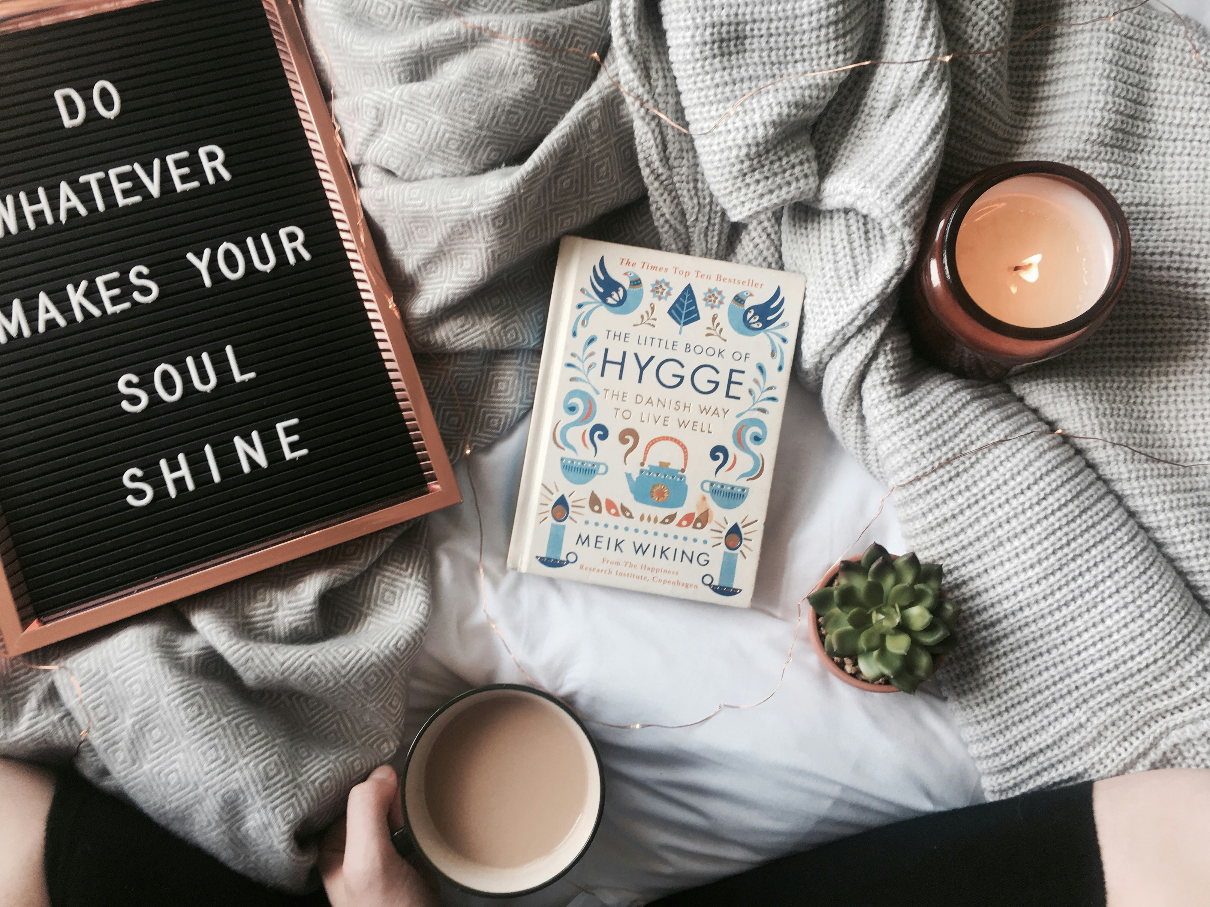 a letterboard reading do whatever makes your soul shine beside a candle and a book