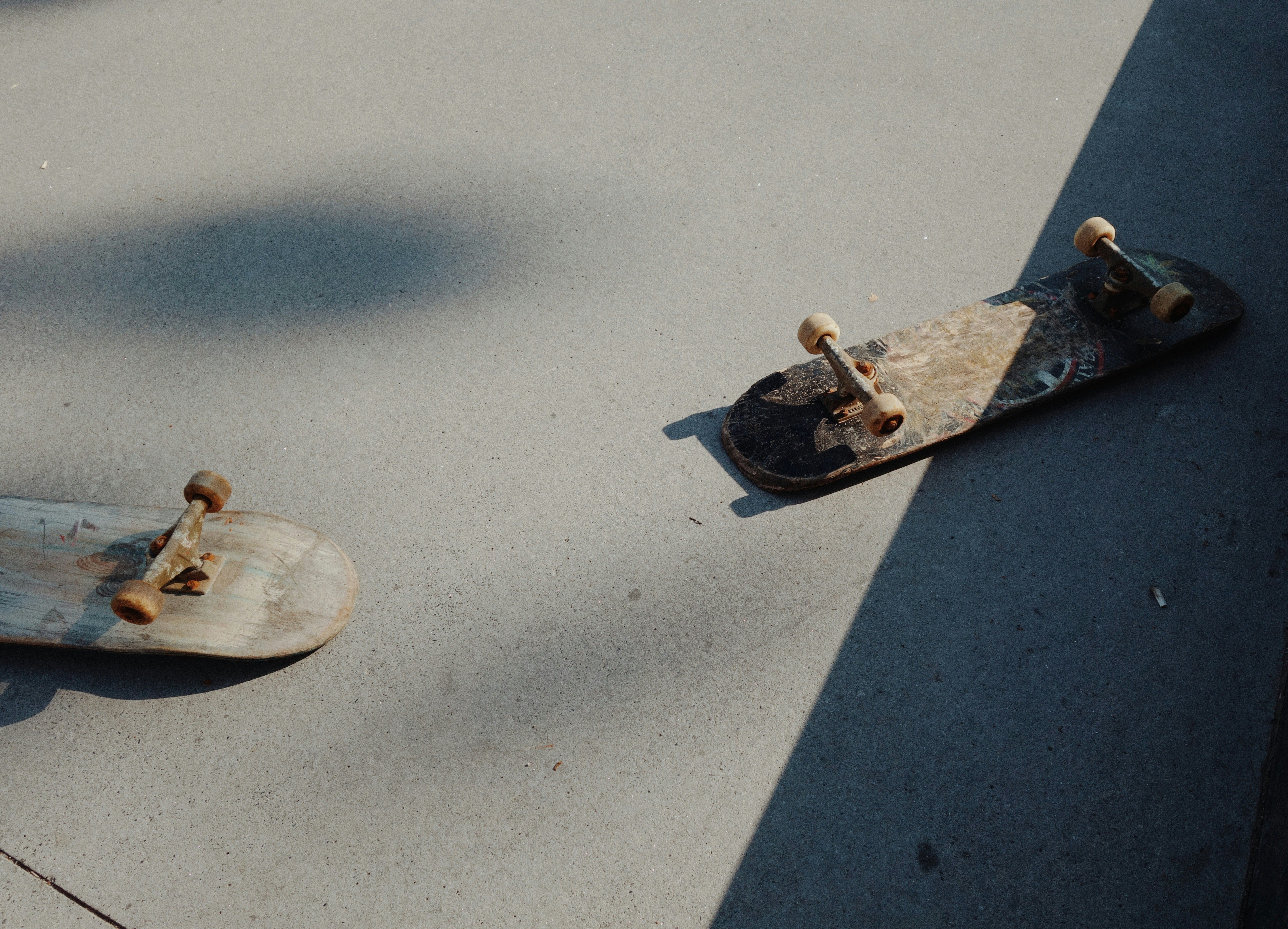 two skateboards left on a concrete slab in hard afternoon light