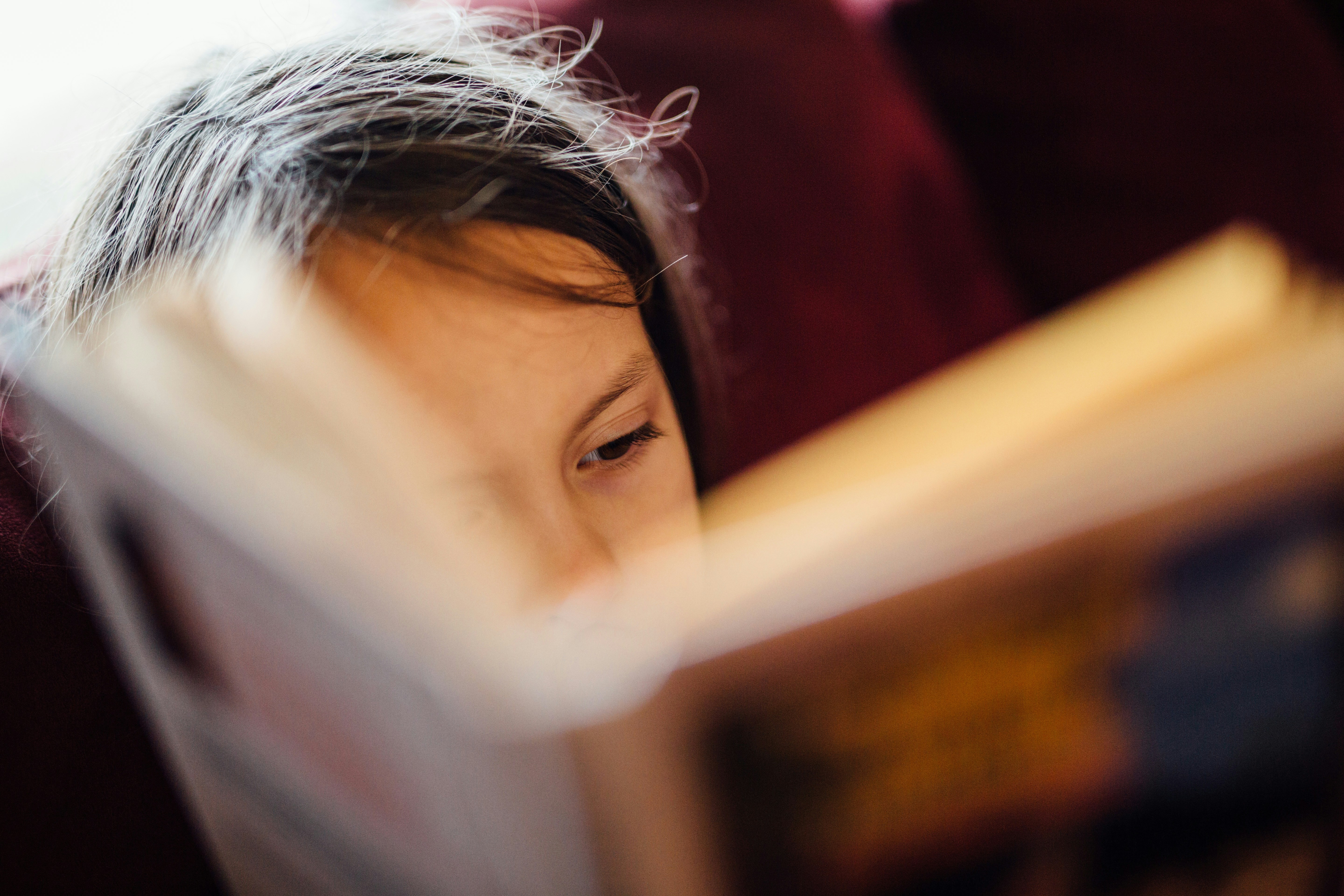 a child reading, half hidden behind the book