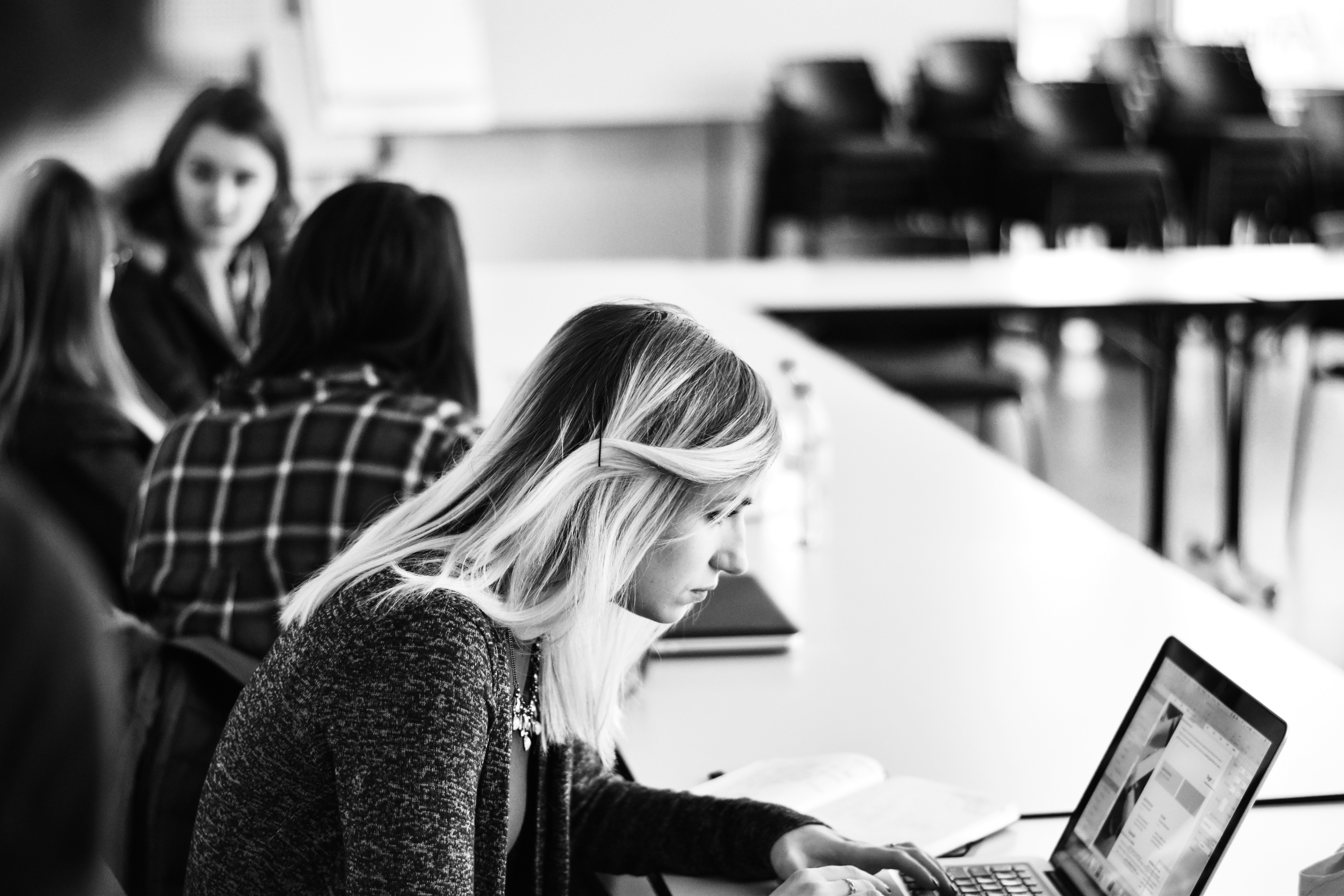a woman working on a laptop in a busy shared space