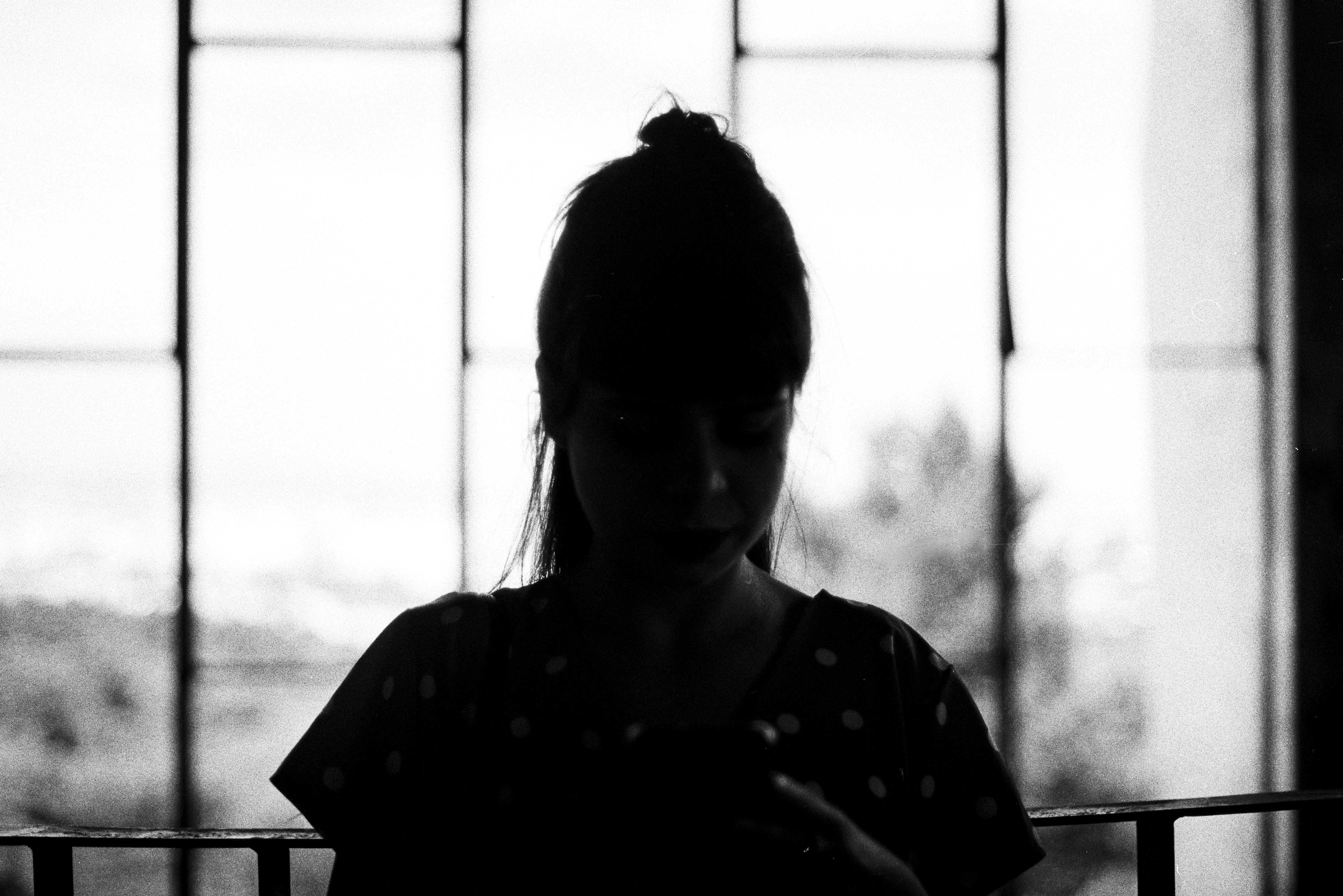 a silhouetted figure standing at a tall window