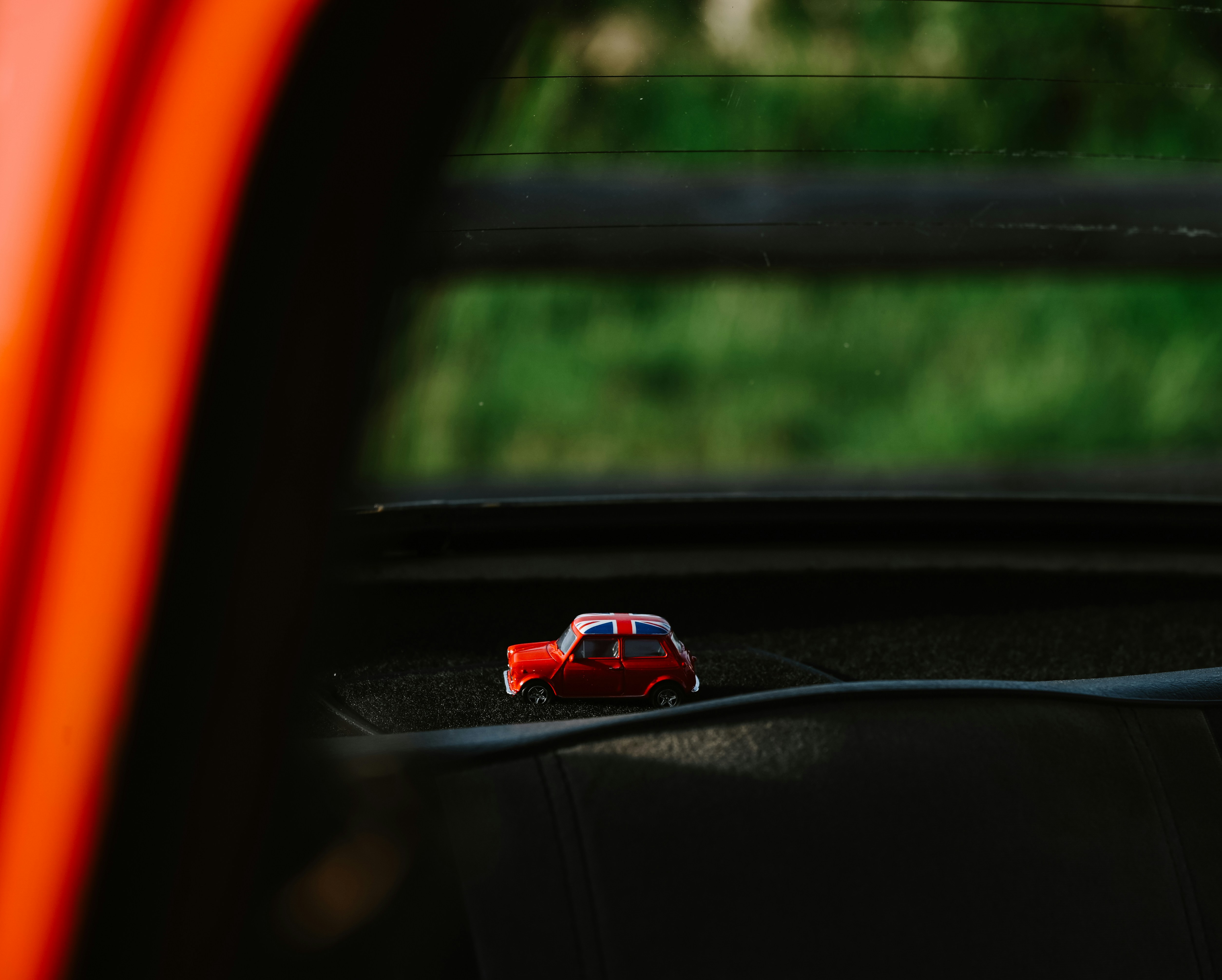 a small toy car on a windowsill in a moving vehicle
