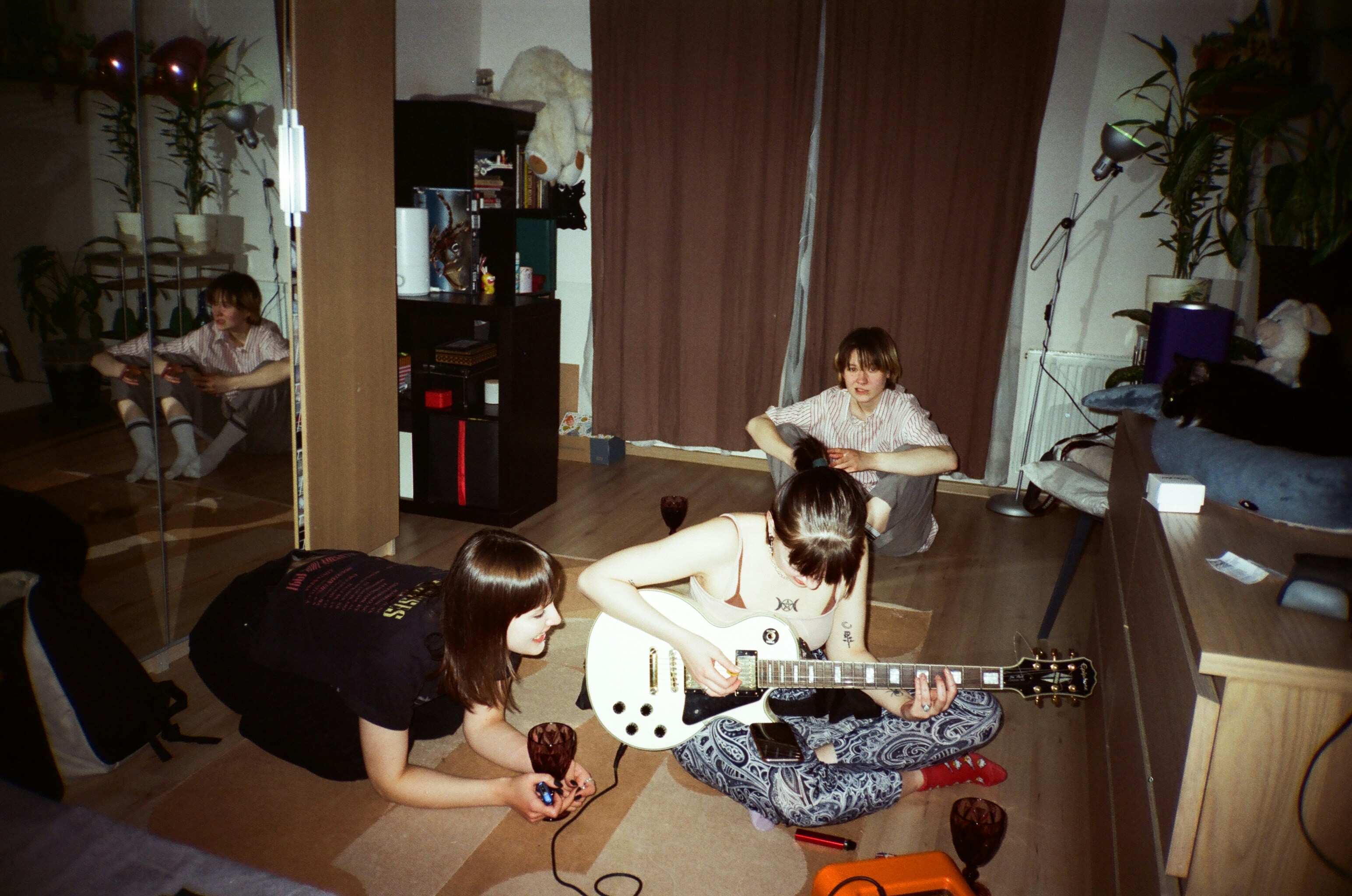 teenagers playing guitar together on a bedroom floor