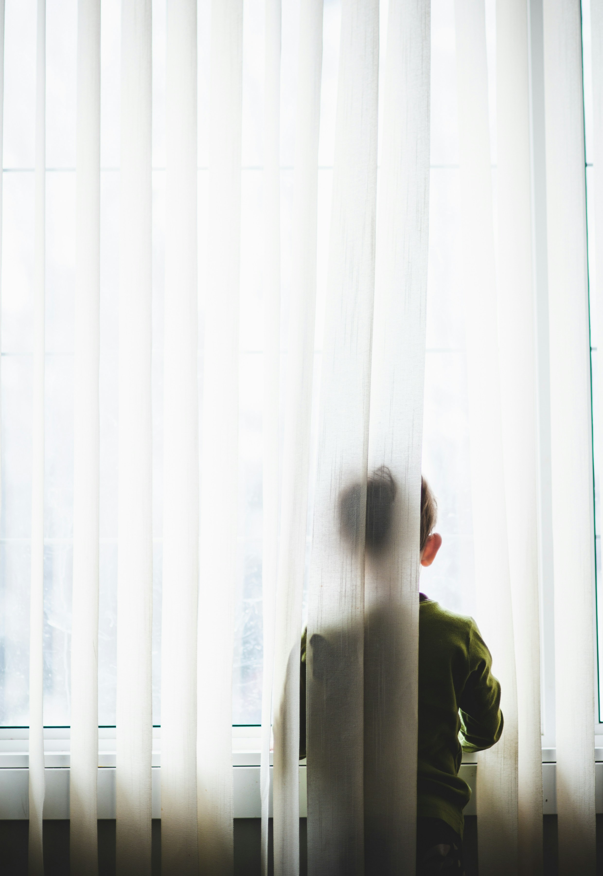a child half-hidden behind a curtain