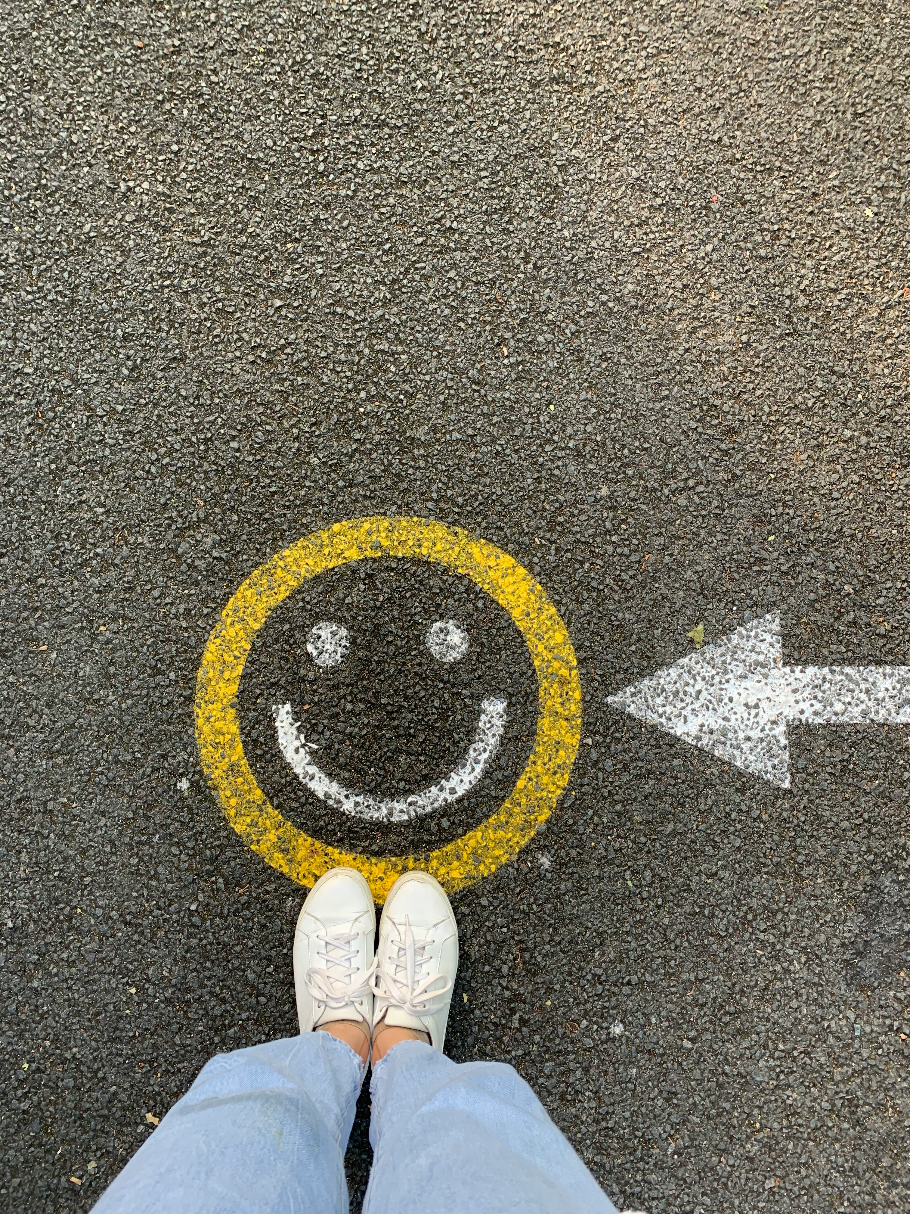a smiley face and arrow painted on the pavement, seen from above