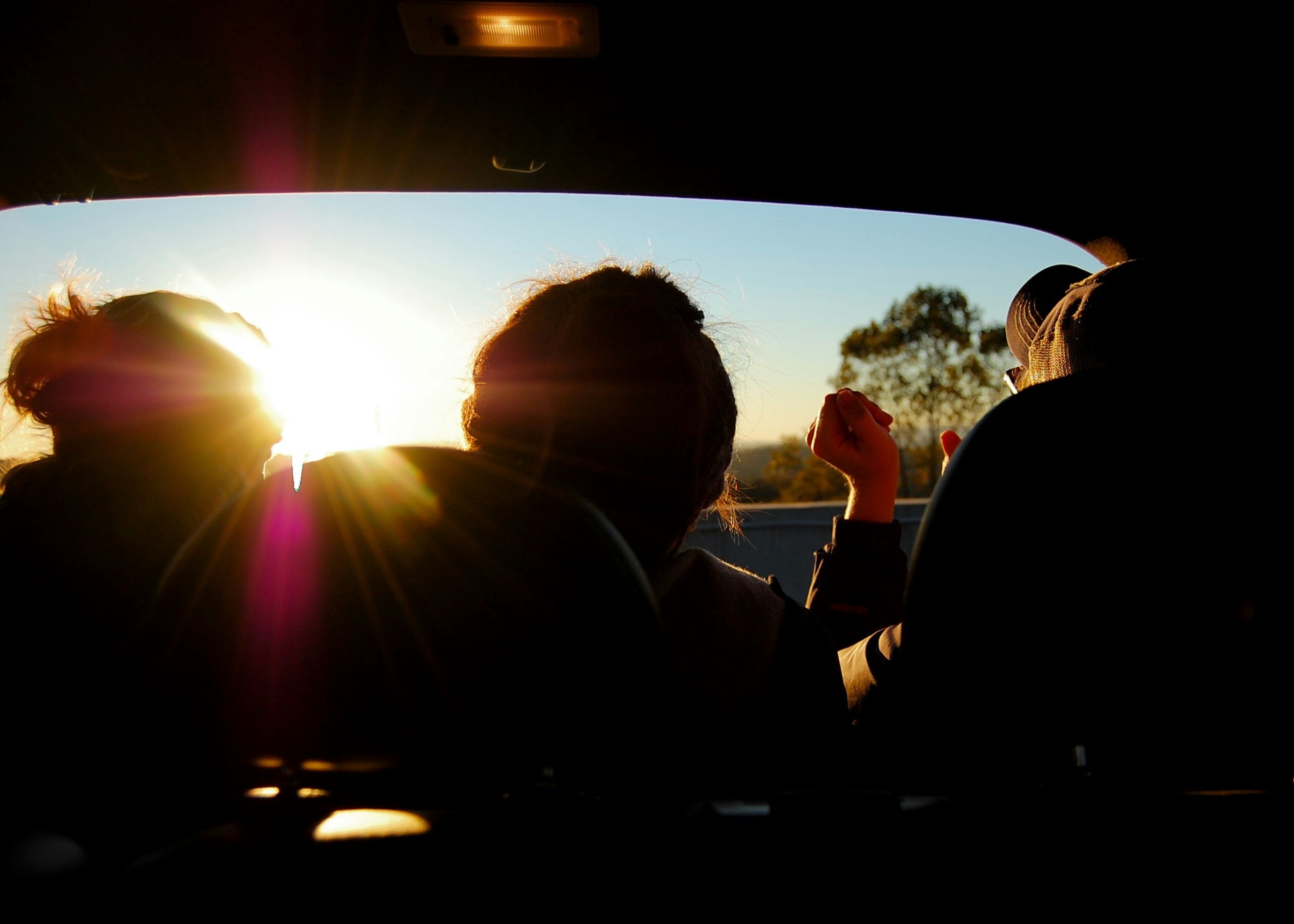 friends sitting together in a car as the sun goes down
