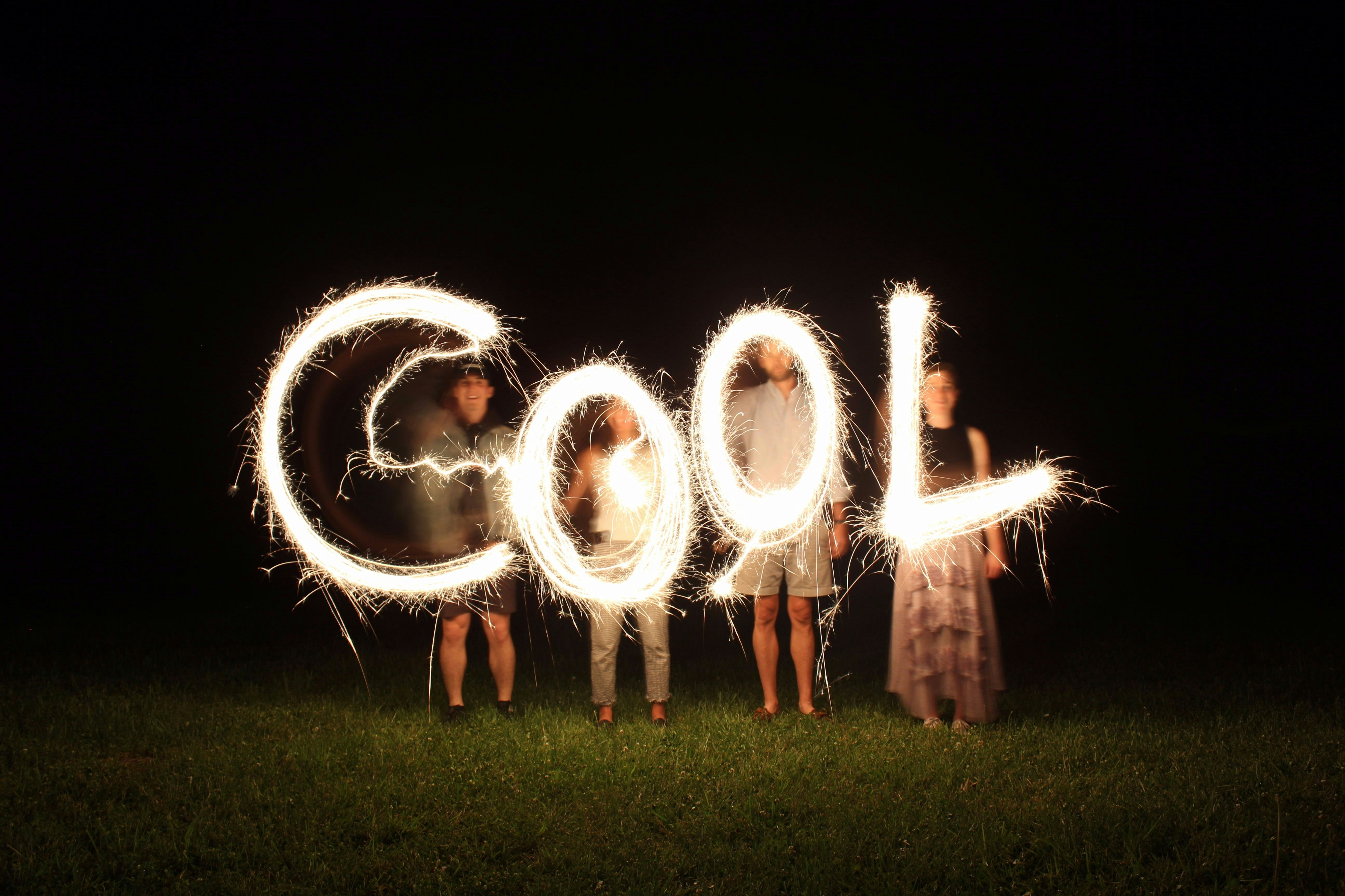 friends writing the word cool with sparklers in the dark