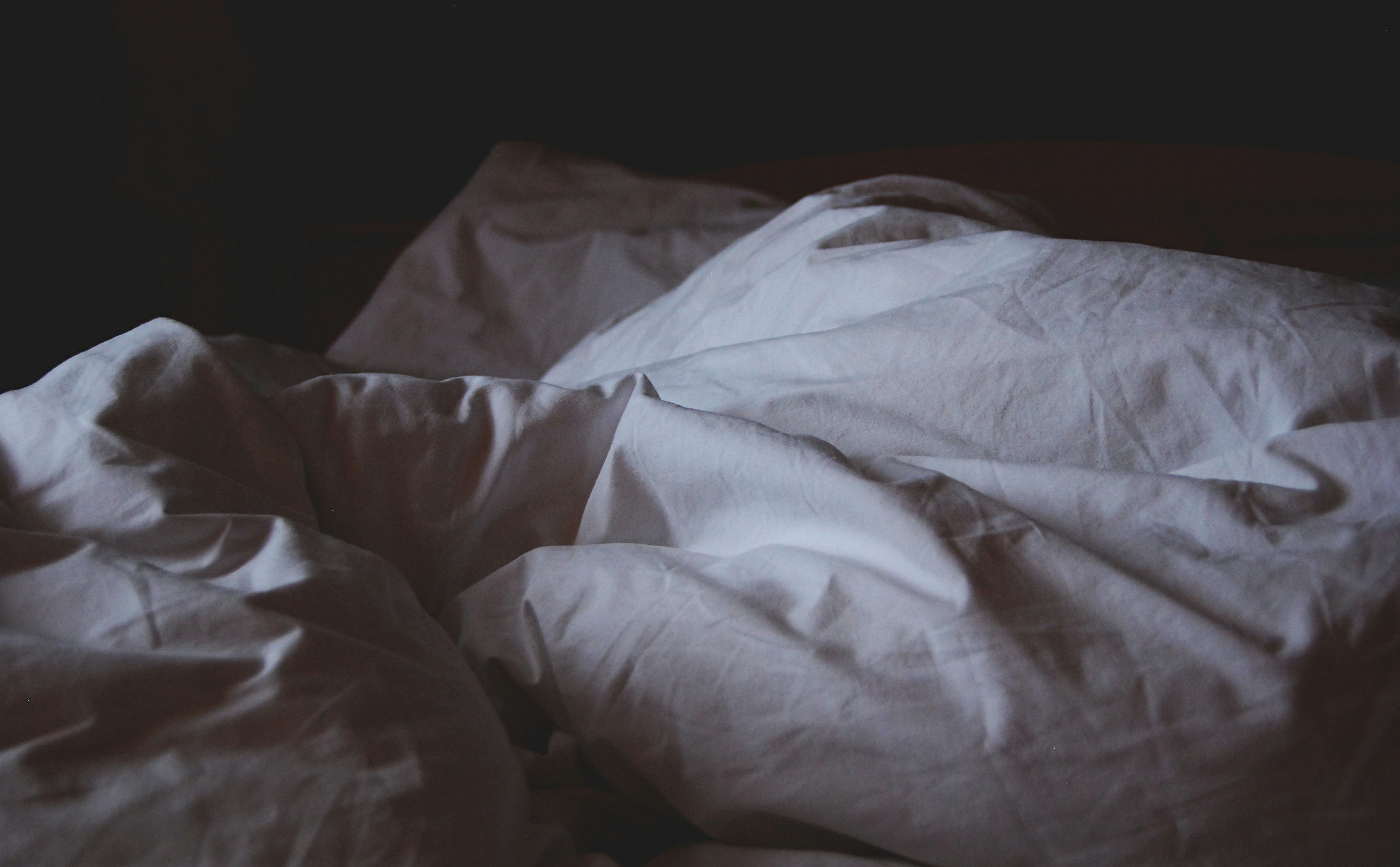 a rumpled white duvet in dim morning light