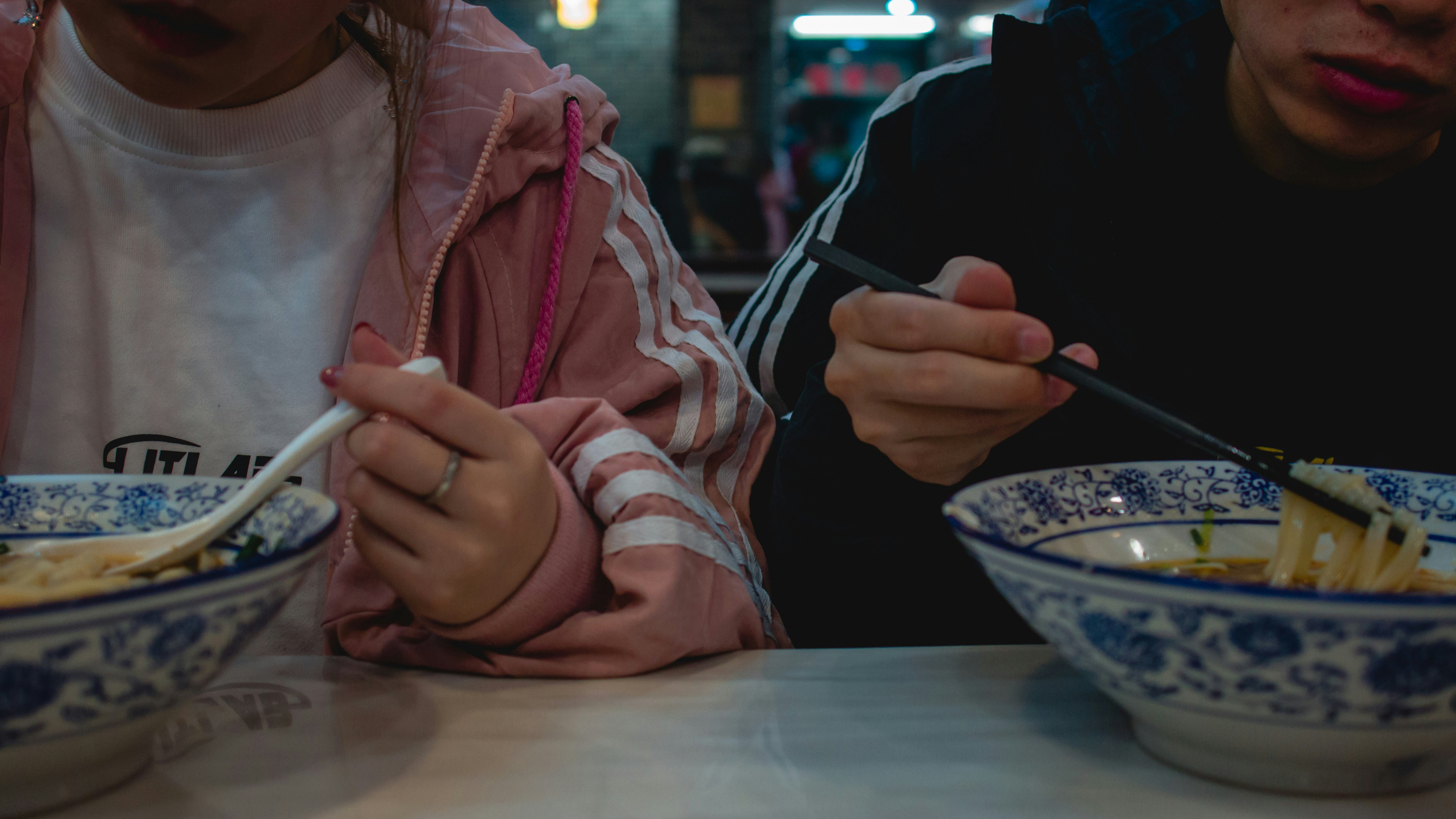 a child and adult eating noodles together at a night market
