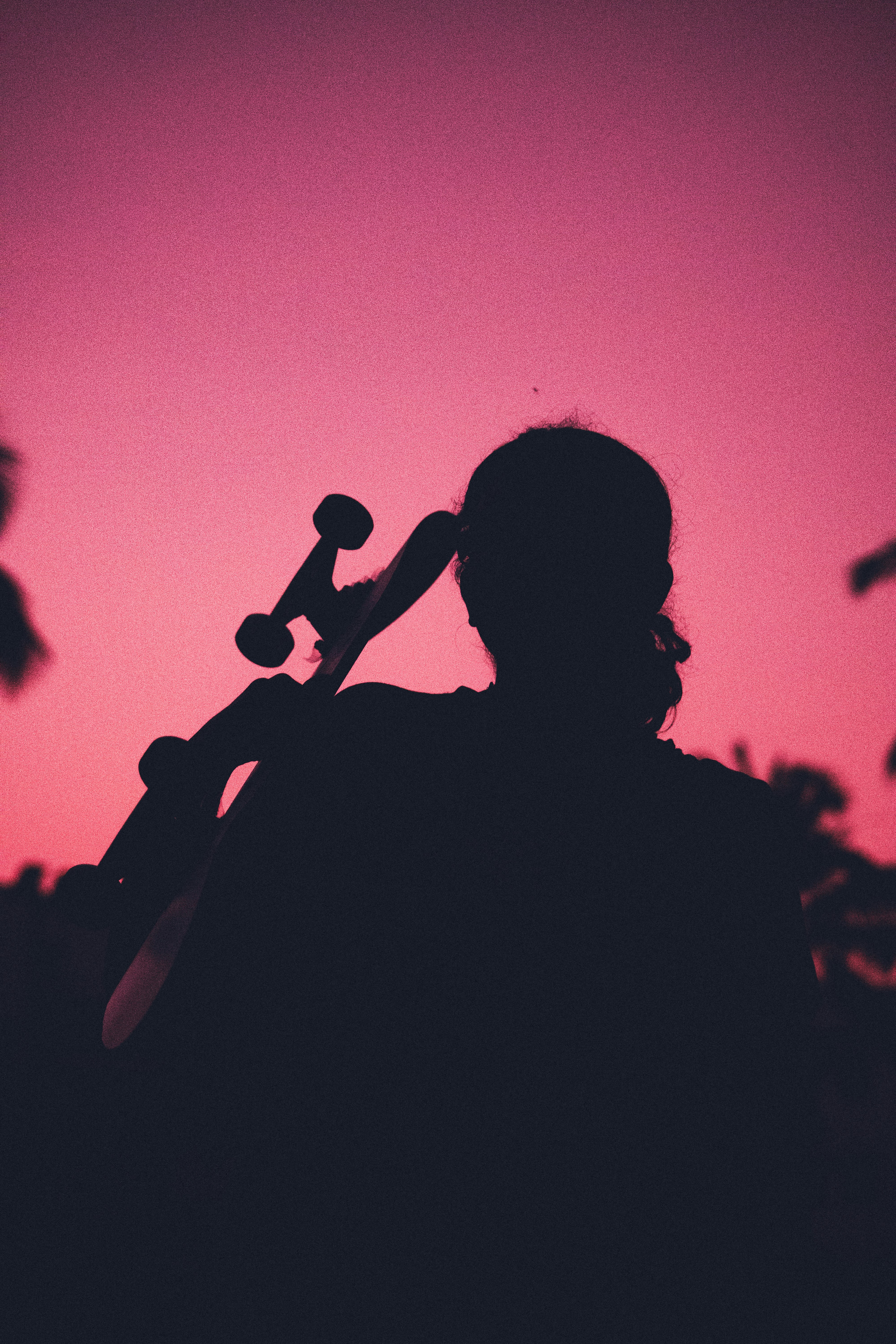 a silhouetted cellist against a deep pink sky