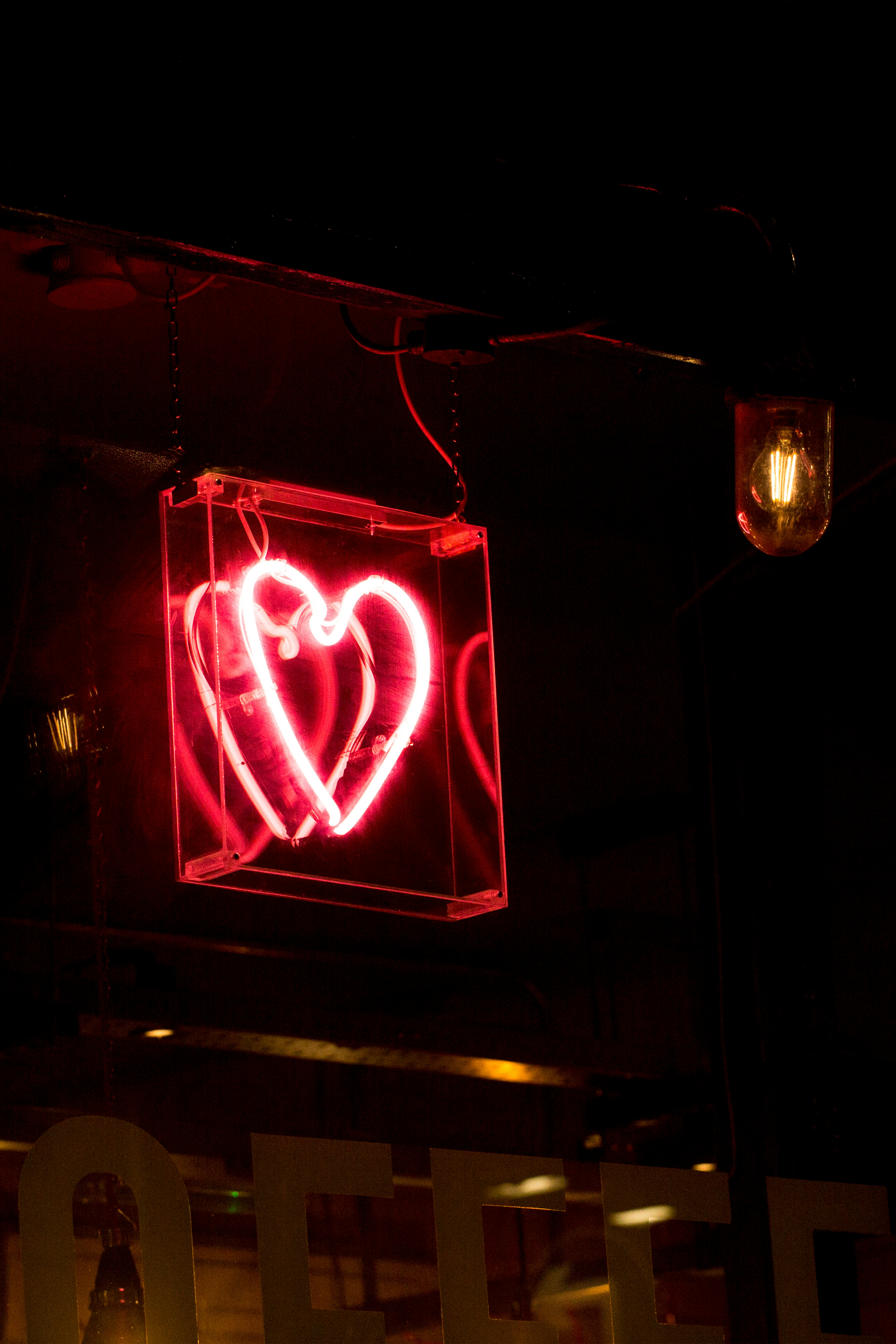 a neon heart sign glowing in a dark window