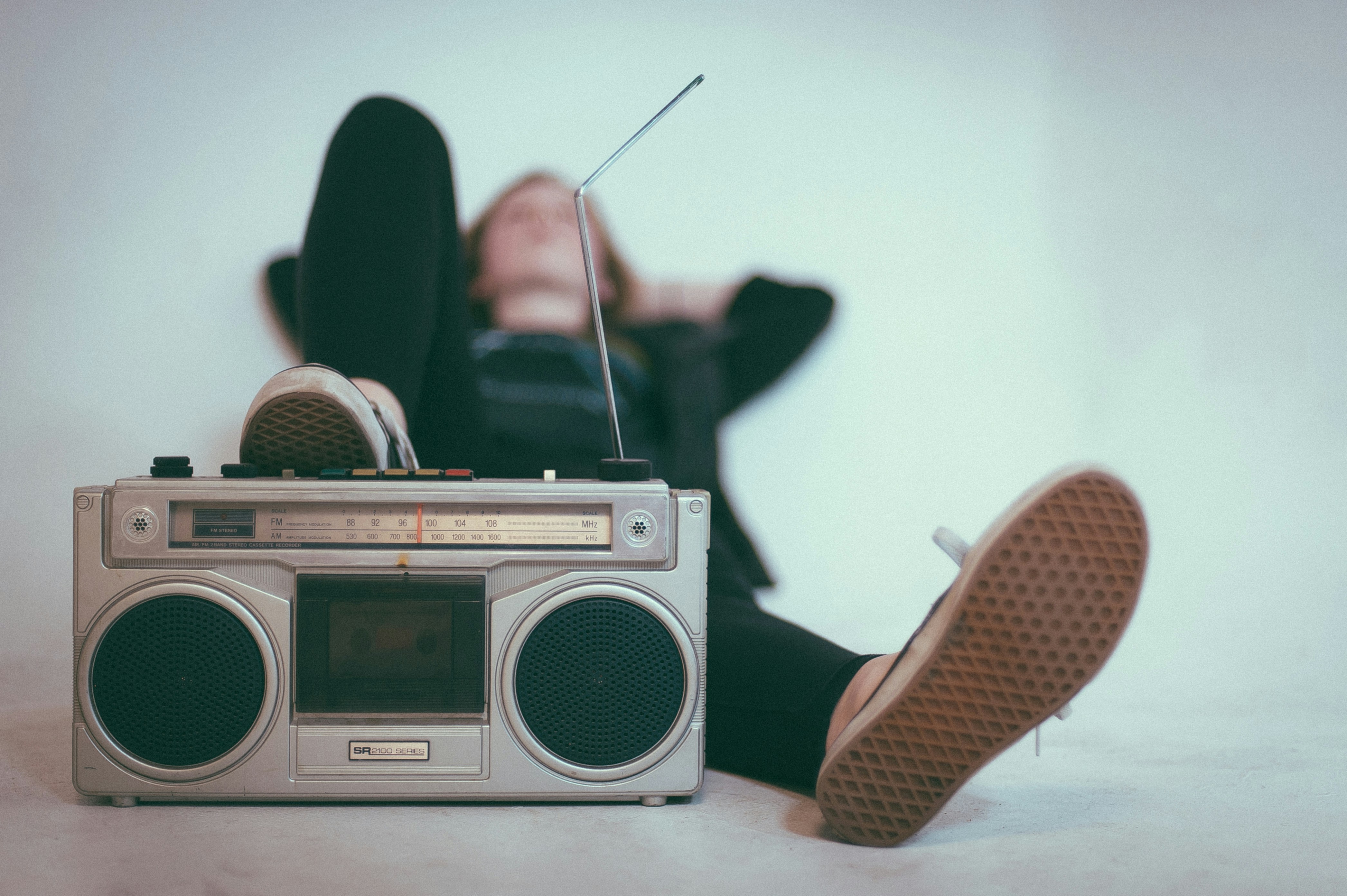 a teenager lying back on the floor beside a boombox