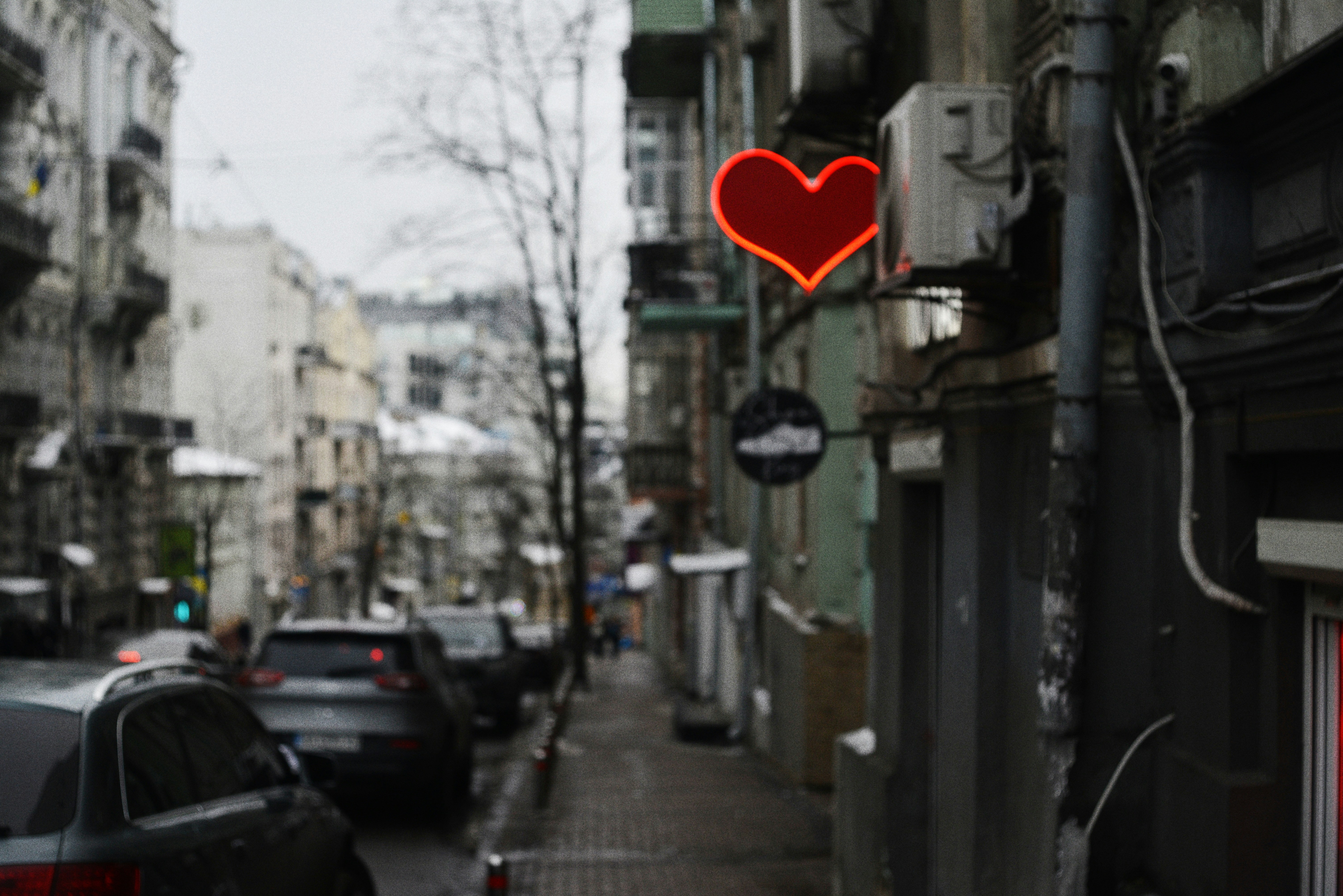 a red heart sign hanging above a quiet city street