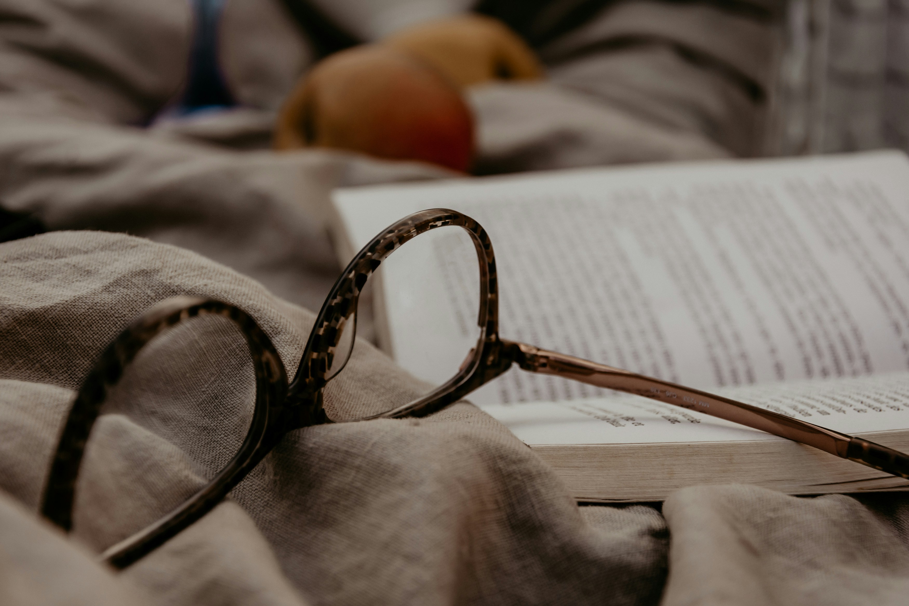 glasses resting on an open book and blanket
