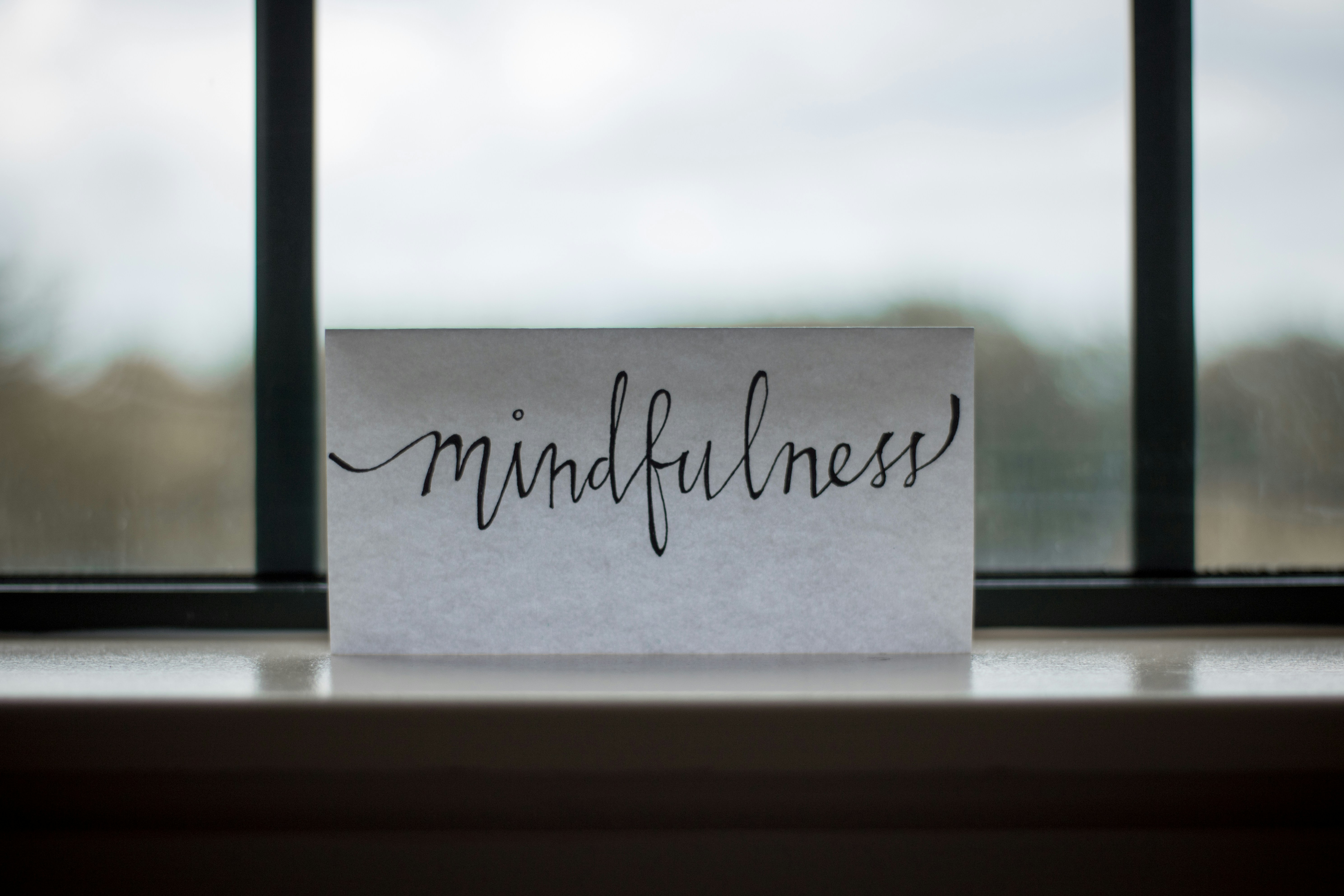 a handwritten card reading mindfulness propped on a windowsill