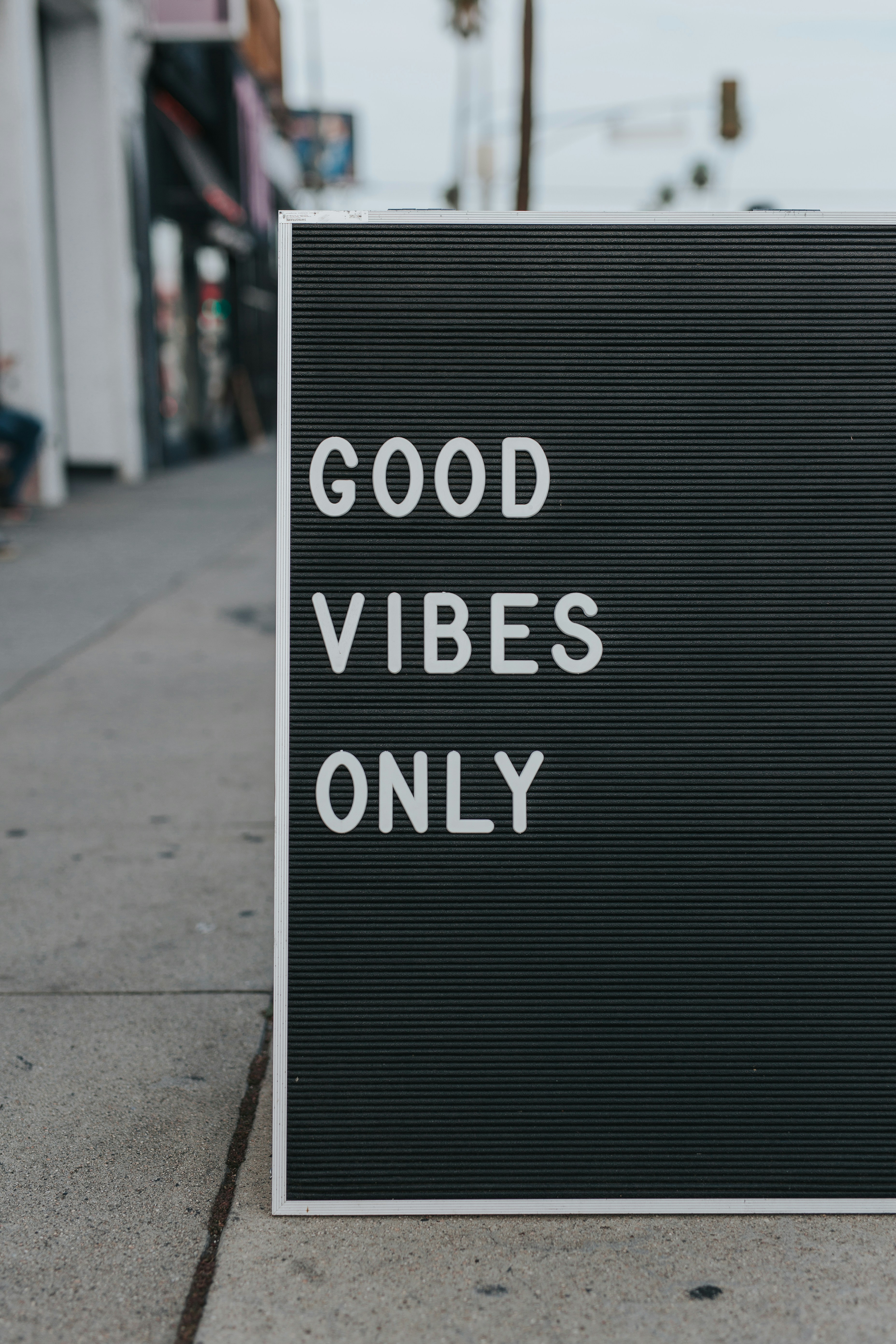 a letterboard sign on a pavement reading good vibes only