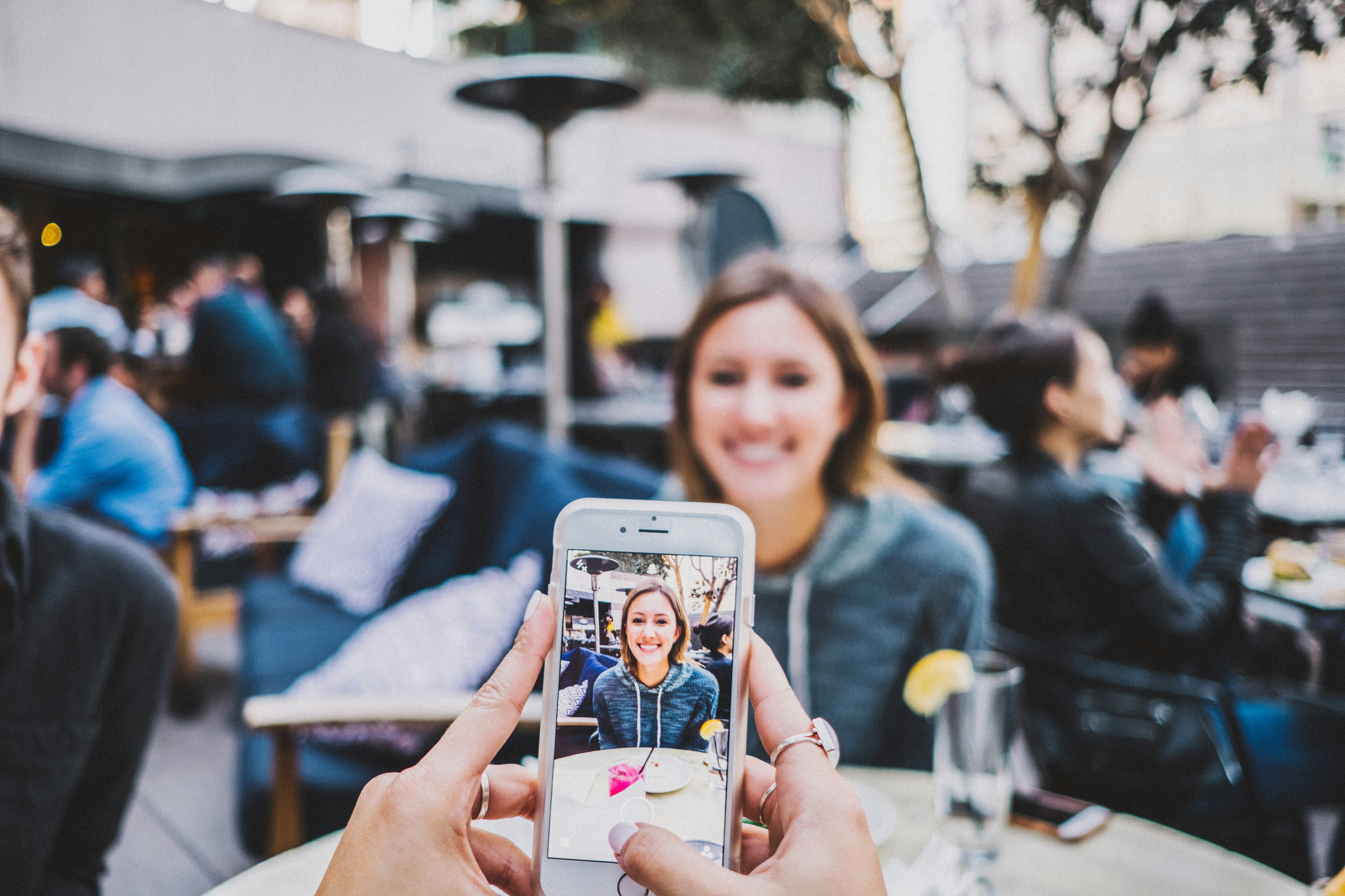 someone photographing a friend across a cafe table