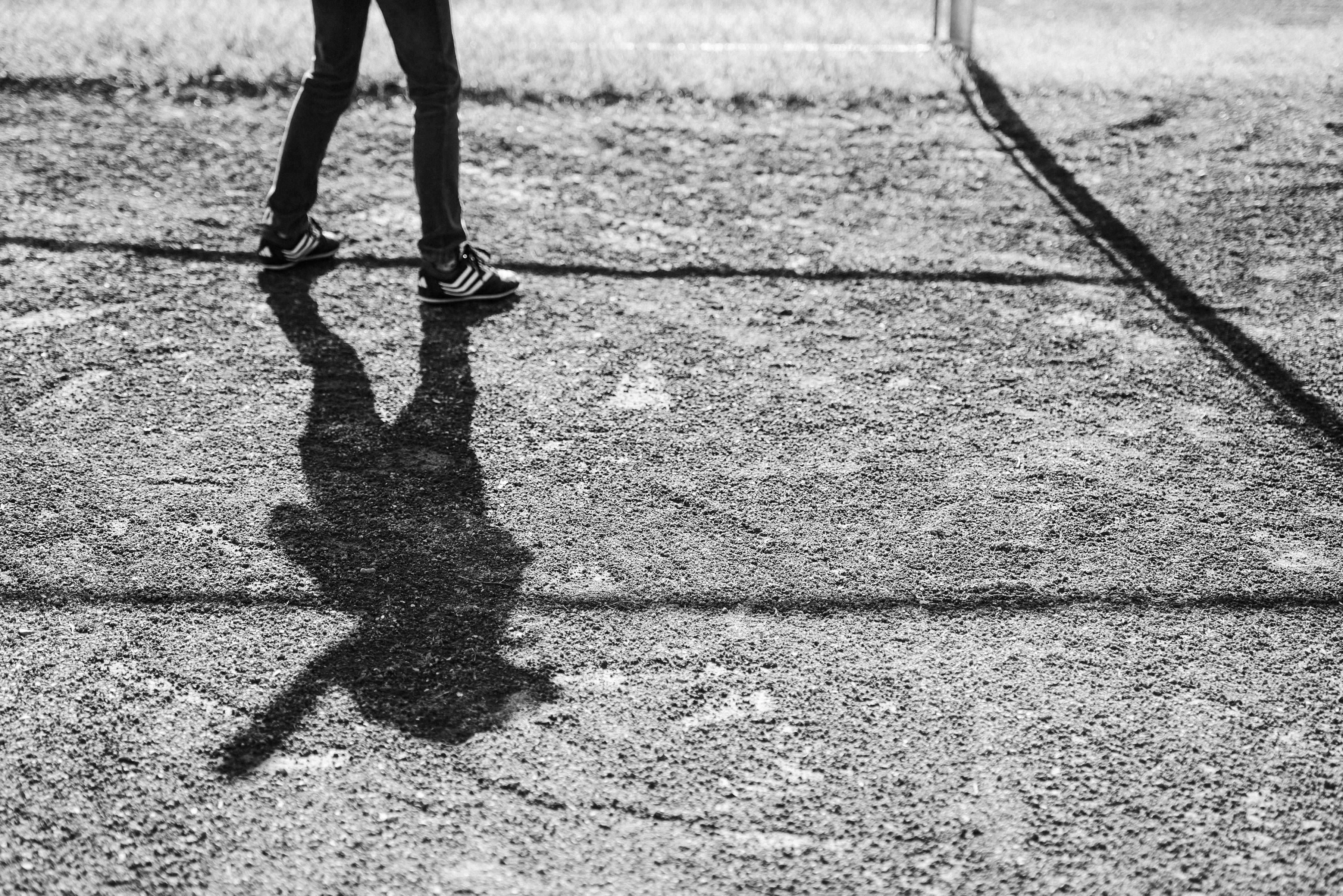 the shadow of a person walking on tarmac
